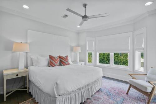 a white bedroom with a bed and a chair at 80 Blue Sky in Santa Rosa Beach