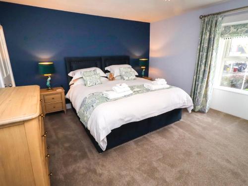 a bedroom with a large bed with blue walls at Linn Cottage in Hexham