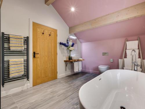 a bathroom with a white tub and a wooden door at 3 Bed in Otley oc-g0176 in Timble