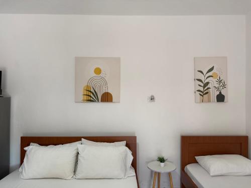 a bedroom with two beds and three paintings on the wall at Rent rooms Loren in Vlorë