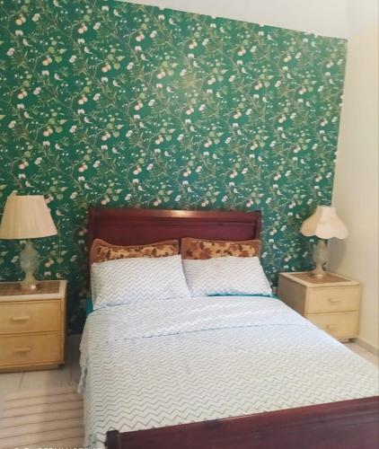 a bedroom with a bed and a green wall with flowers at Privat 3 bedroom apartment in Sosua