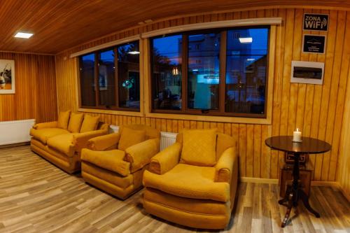 a room with two chairs and a table andwindows at Hostal Royal Austral in Coihaique