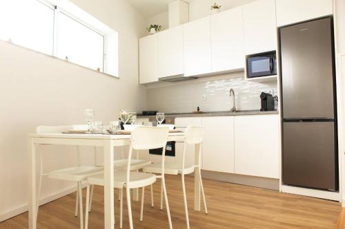 a white kitchen with a white table and chairs at Valbom Hideaway Light, Style and Peace in Valbom