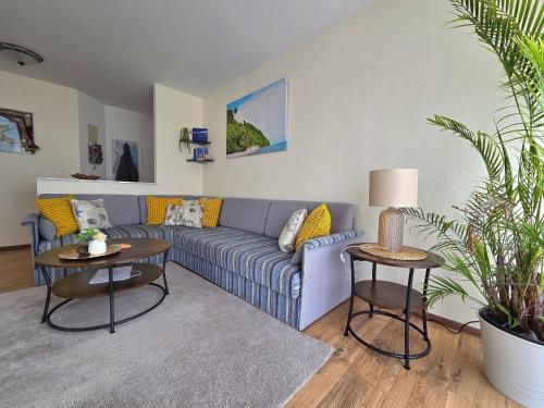 a living room with a blue couch and two tables at Komfortferienwohnung Kreideblick in Sassnitz
