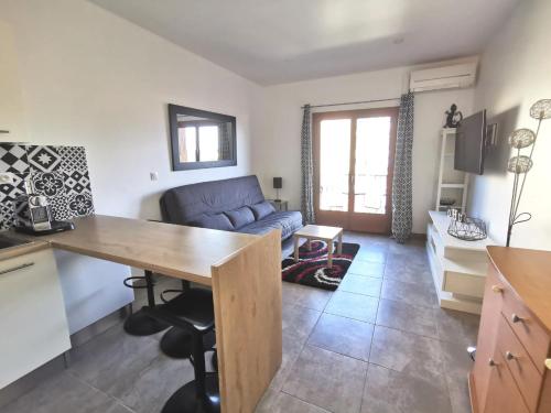 a kitchen and living room with a couch and a table at Studio Serenity - Clim - WIFI - Parking - Piscine - Front de mer - Proche commerces et centre ville in Fréjus