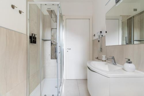 a white bathroom with a sink and a shower at Elegant Lake View Apartment with Pool in Lavena Ponte Tresa