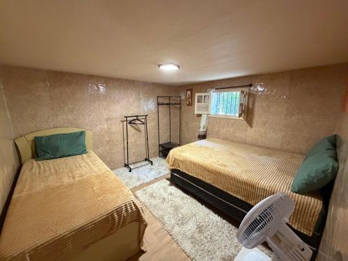 a small room with two beds and a fan at Cantinho do Imperador in Petrópolis