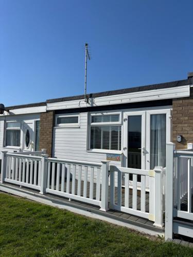 a white mobile home with a white fence at 288, Two bed Chalet on Belle Aire Holiday Park - With private veranda, sleeps 5, pet friendly, free Wi-Fi, bed linen and towels included and onsite entertainment available in Hemsby