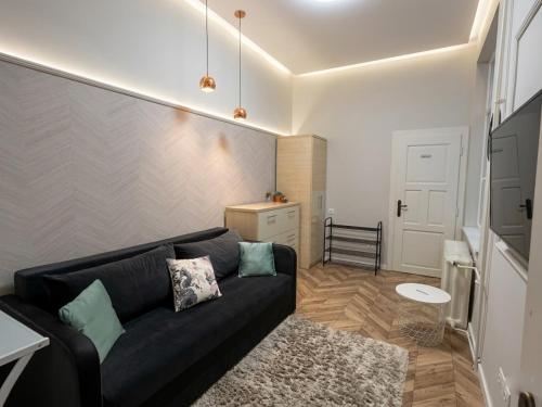 a living room with a black couch in a room at Visit Debrecen Apartman in Debrecen