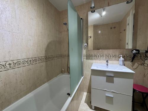 a bathroom with a sink and a tub and a mirror at Apartamento Benalmarina in Benalmádena
