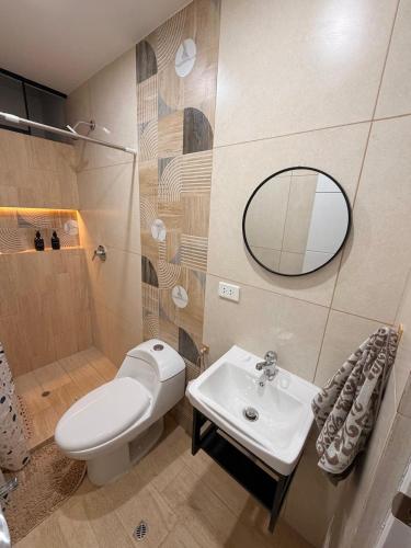 a bathroom with a toilet and a sink and a mirror at Dpto familiar moderno 2do piso - 2 Hab - 3 camas - wifi - lavadora in Tacna