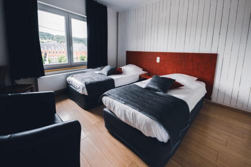 a hotel room with two beds and a chair at L'Auberge Saint Remacle in Stavelot
