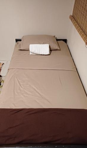 a bed with a tan sheet and a white pillow at Donde Dubon Pandi house in Puerto Jiménez