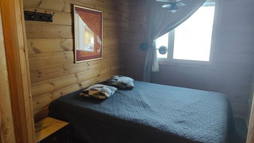 a bedroom with a blue bed and a window at Kaijonselän mökit Pyhitty in Vehmaskylä