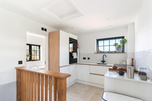 a kitchen with white cabinets and a sink at Cosy Nook at Jam Jar Kitchen in Crantock