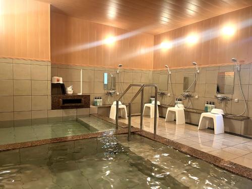 a bathroom with a pool of water with sinks and toilets at Nobeoka Urban Hotel in Nobeoka