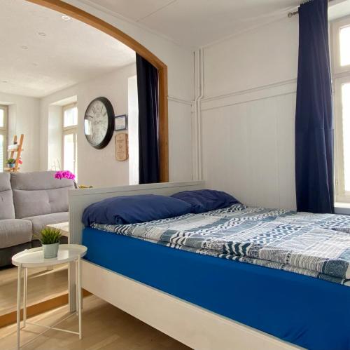 a bedroom with a blue bed and a couch at Studio Frohburg Gommiswald in Gommiswald