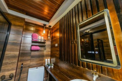 a bathroom with wooden walls and a sink and a mirror at Jhenk's Guesthouse in Coleto