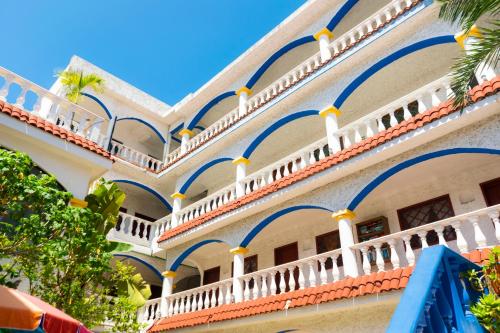 a white building with blue and white balconies and palm trees at Villa Madre by La Cultura Suites - Hotel Moms in Playa del Carmen
