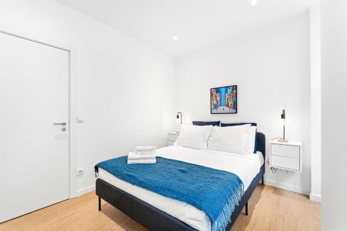 a white bedroom with a bed with a blue blanket at GuestReady - The Olives in Coimbra
