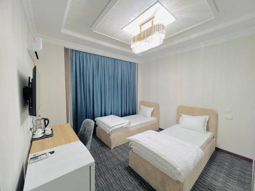 a hotel room with two beds and a desk at Volidam Hotel in Qarshi