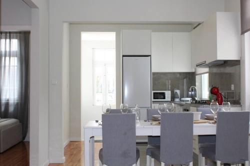 a kitchen with a table with chairs and a kitchen with white cabinets at 1000Jo Apartment T3 in Gulpilhares