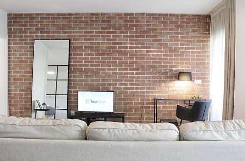 a living room with a couch and a brick wall at Arrábida Luxury Studio in Vila Nova de Gaia