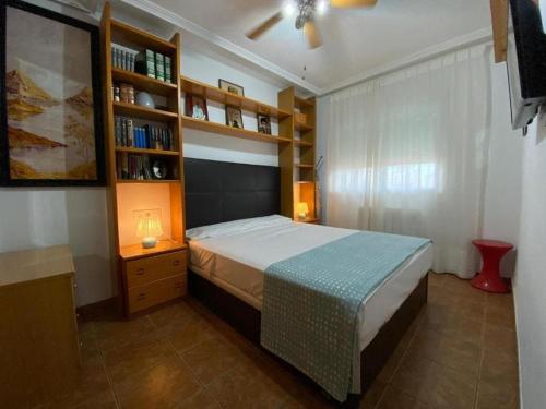 a bedroom with a bed and a book shelf at Apto 1 Hab, Terraza & Piscina, 5 min Playa in Playa de Gandia