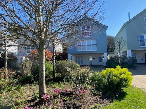 a house with a tree and flowers in a yard at 6 The Salterns - Yarmouth in Freshwater