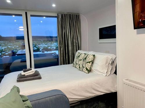 a small bedroom with a bed and a large window at The Lux Pod in Ballynameen