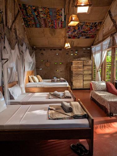 a bedroom with two beds and a couch in a room at Backyard Eco Bungalows Moshi in Moshi