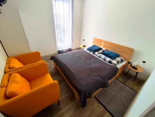 a bedroom with a bed and a orange chair at Comfort Apartment for 6 & Loggia & Free Parking in Žilina