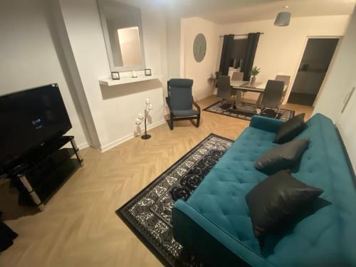 a living room with a blue couch and a television at Alliance house OVER 25 ONLY kids with adults allowed in Belfast