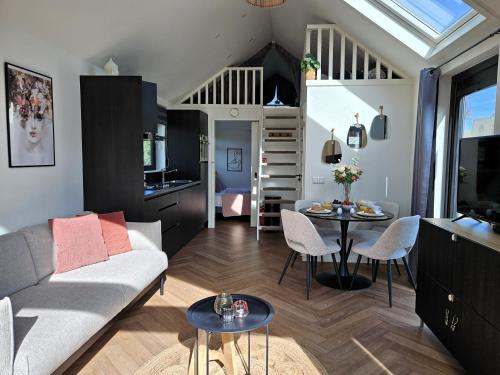 a living room with a couch and a table at Tiny Zen House in Heinkenszand with private sauna, airco, outdoor swimming pool, WiFi and 2 bedrooms in Heinkensand
