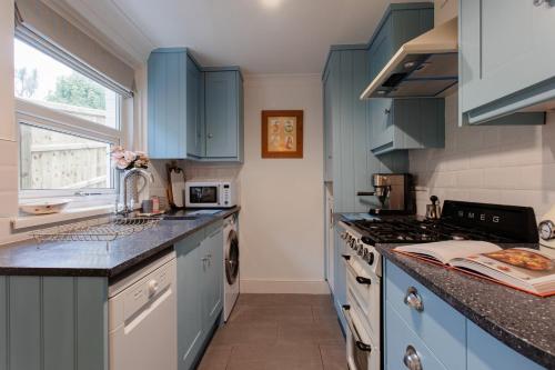 a kitchen with blue cabinets and a stove at Didis Cottage-Dog Friendly-Garden-Cowes-Sleeps 4 in Cowes
