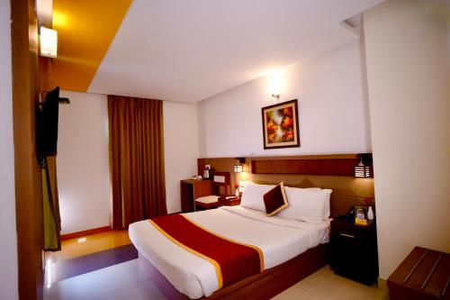 a hotel room with a bed and a television at Hotel De Grand Malabar in Kozhikode