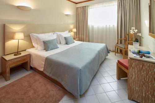 a hotel room with a large bed and a window at Luna Clube Oceano in Albufeira