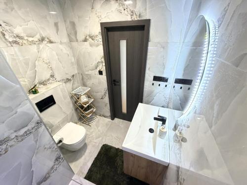 a white bathroom with a toilet and a sink at Sky View Apartmán 10 patro in Břeclav