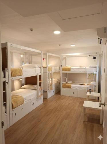 a room with white bunk beds and a wooden floor at Vivian's Guest House Auto Check-in in Jerez de la Frontera