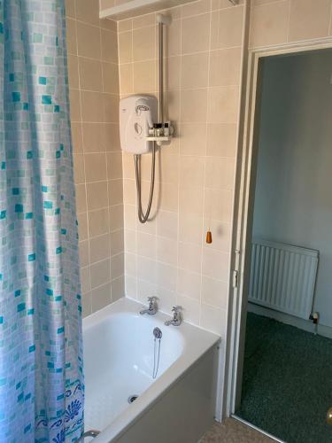 a bath tub in a bathroom with a shower at The Phelips Arms in Montacute