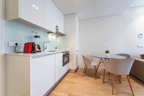a kitchen with white cabinets and a table and chairs at Antas Park Flat With Pool in Porto