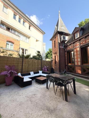 a patio with couches and a table and a building at Manoir Loft pour vos événements in Nanterre