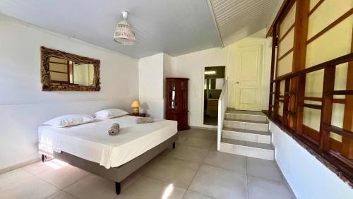 a bedroom with a bed and a mirror and a staircase at Moorea - Temae Reef Cottage in Temae