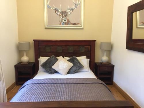 a bedroom with a bed with two nightstands and a deer picture at Waters Edge Cottage in Alexandria