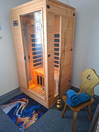 a wooden shower stall in a room with a chair at Mia Apartman Salgótarján in Salgótarján