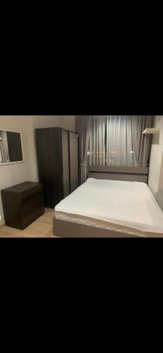 a bedroom with a white bed and a night stand at Perfectly Located Airport Link Train City Access in Bangkok