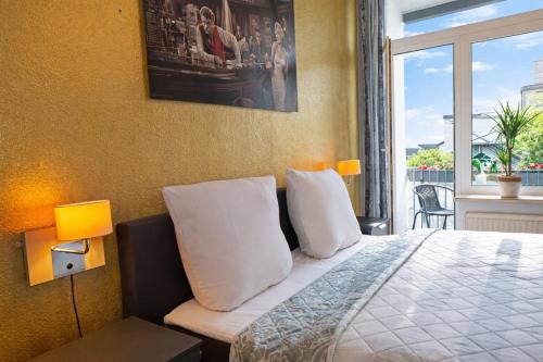 a bedroom with a bed with white pillows and a window at fewo1846 - Royal Suite - Stilvolle Wohnung mit 2 Schlafzimmern im Stadtzentrum in Flensburg