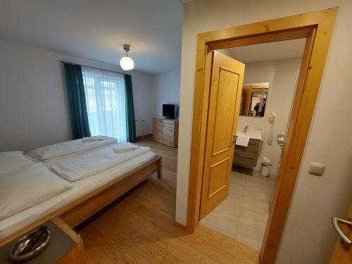 a bedroom with a bed and a bathroom with a sink at Alpen Appartements in Embach