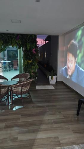 a large screen with a man on a wall in a building at Lugar Aconchegante 3 in Palhoça