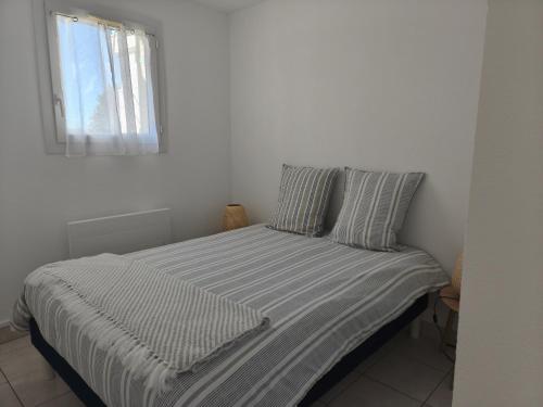 a bed in a white room with a window at T2 L'orée du Golf labellisé 3 étoiles - Terasse et Parking in Pornic